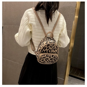 Detailed view of leopard print mini backpack styled with white knit sweater and black skirt