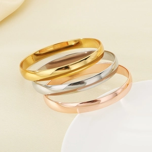 Minimalist gold, silver and rose gold stainless steel bracelets stacked in macro view