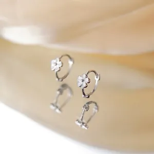 Silver flower huggie earrings with white petals on elegant champagne silk fabric