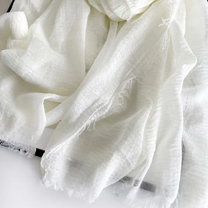 Close-up of pure white cotton linen scarf showing soft breathable texture and fringe