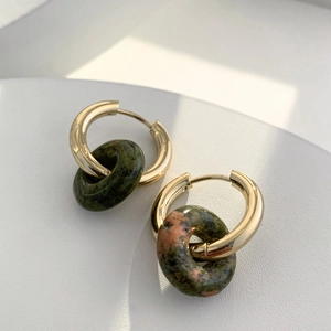 Detailed close-up of 18K gold hoop earrings with donut-shaped ruby zoisite stone pendants