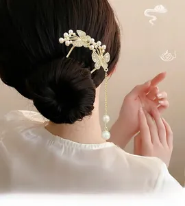 Détail d'épingle à cheveux papillon dorée avec glands et perles sur un chignon