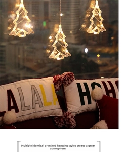 Three LED Christmas tree window lights with warm white glow hanging over festive cushions
