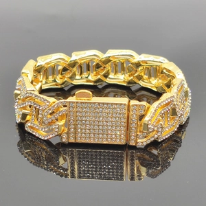 Macro detail of gold-plated cuban link chain with sparkling rhinestones on black surface