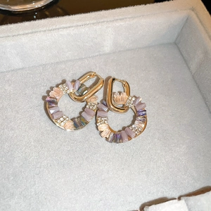 Detail of gold hoop earrings with pink and purple crystals and shimmering rhinestones