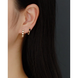 Close-up of gold twist hoop earrings with black teardrop gem and sparkling crystals