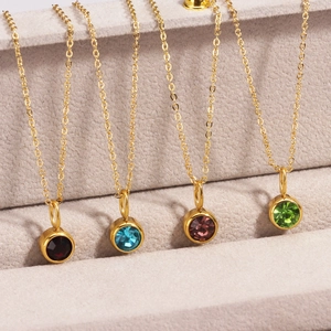 Close-up of gold birthstone necklaces with red, blue, purple, and green gems on velvet