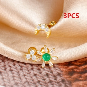 Macro shot of 3pcs gold ear studs set with moon and sun designs and green zircon