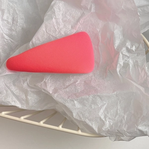 Detailed view of a matte red triangular hair clip on a minimalist white background