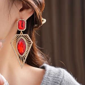 Macro shot of vintage gold drop earrings with red gemstones and sparkling rhinestones