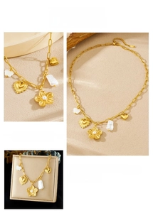 Détail d'un collier doré vintage avec fleur en perle et pendentifs cœur sur chaîne