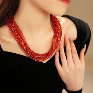 Dettaglio macro della collana a più fili di perline rosso acceso con chiusura magnetica