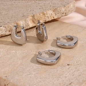 Macro shot of silver U-shaped mirror-polished earrings on decorative stone tiles