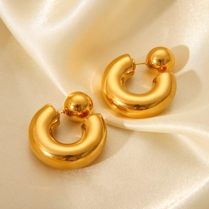 Detail of chunky gold-tone C-shaped stainless steel earrings on a soft cream satin cloth