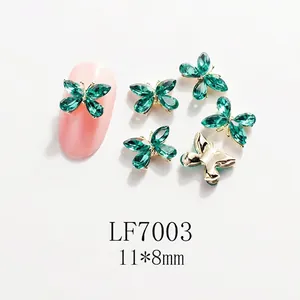 Detalle de joyas para uñas mariposa esmeralda de 11x8mm con base de metal dorado