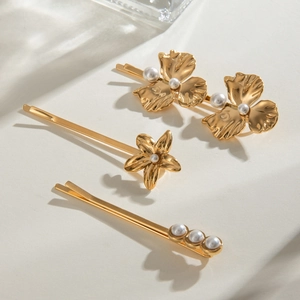 Detail view of 18k gold floral hair clips with white pearls in a three-piece set