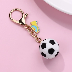 Detailed close-up of a gold keychain with an enamel soccer cleat and a rubber football