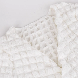 Detailed macro view of white waffle textured fabric and neckline of the two-piece set