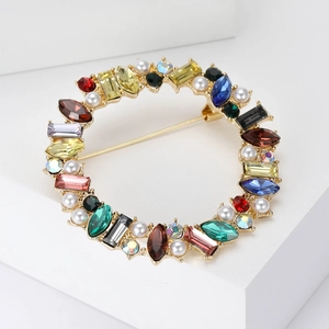Detailed close-up of a circular gold brooch with multi-colored rhinestones and white pearls