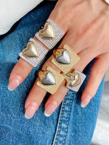 Detail of gold and silver mix heart rings with cubic zirconia pavé on denim background