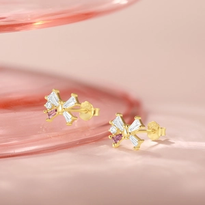 Close-up of golden butterfly studs with pink and clear trapezoid cubic zirconia crystals