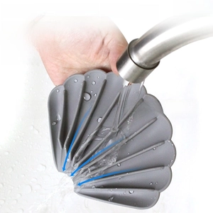 Macro shot of grey shell-shaped silicone soap dish being rinsed under running water