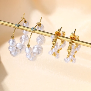 Detailed macro view of gold twisted metal earrings with freshwater pearls on a stand