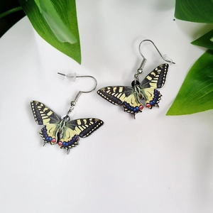 Detailed view of long butterfly wing earrings with vibrant floral patterns on a white base