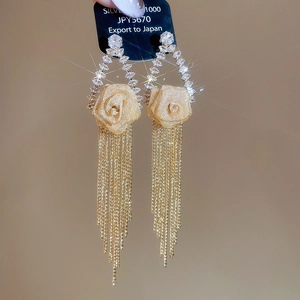 Close-up of gold tassel earrings with fabric rose detail and sparkling zircon studs