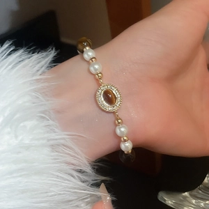Détail d'un bracelet en perles avec pierres œil de tigre, perles et fermoir doré serti