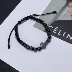 Detail of black beads and metal cross pendant on adjustable cord bracelet for men