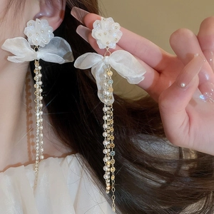 Close-up of white mesh flower earrings with organza bows and pearl tassel details