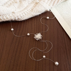 Détail du collier à pampilles en perles argentées avec pendentif tournesol sur bois