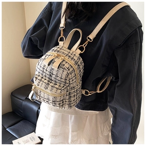 Detail of tweed mini backpack with cream leather straps and gold metal hardware accents