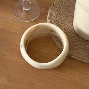 Bracelet large irrégulier en résine avec texture crème et ambre sur bois