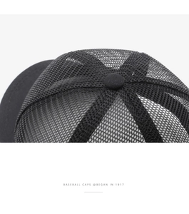 Detail of black mesh baseball cap showing breathable texture and reinforced top stitching