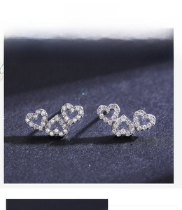 Macro view of triple-layered hollow heart stud earrings with sparkling micro-inlaid stones