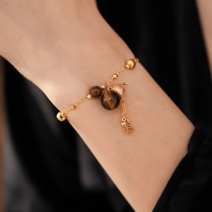 Detailansicht des Tigerauge-Armbands mit Goldfinish und Kalebasse am Handgelenk