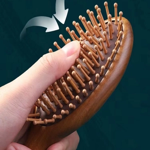 Close-up of a wooden cushion hairbrush being pressed to show scalp massage elasticity