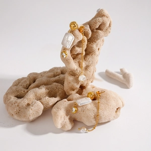 Detailed shot of gold earrings with baroque pearls and zircon charms on coral display