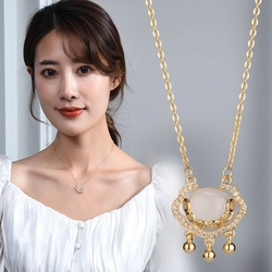 Detail of gold Ruyi lock necklace with white gemstone and small diamond accents