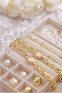 Detail view of gold chain watches with green jade stones in a velvet jewelry box