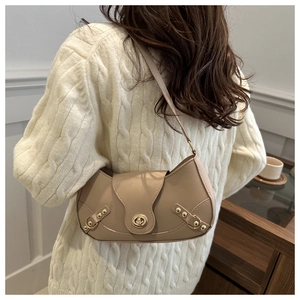 Back view of a beige leather dumpling bag with metal buckle on a model in a home setting