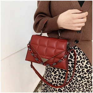Detail of red quilted handbag with metal triangle buckle and resin chain handle