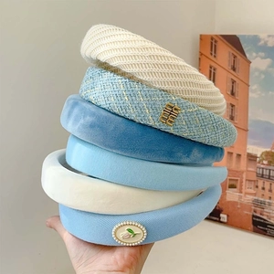 Blue and beige padded headbands in tweed and velvet fabrics stacked for a high top look
