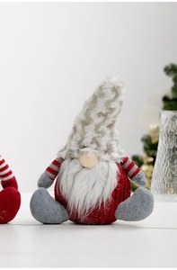 Detail of red knit Christmas gnome decoration with a long white beard on white surface
