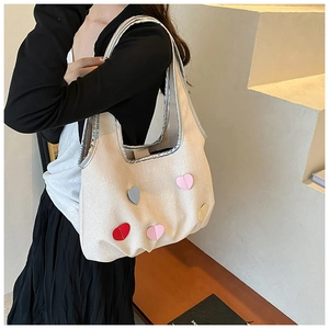 Détail du sac cabas en toile crème avec patchs cœurs colorés et finitions argentées