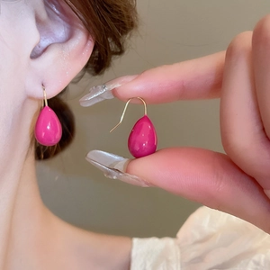 Minimalist fuchsia waterdrop earrings with gold-plated hooks shown in a high-quality hand-held view