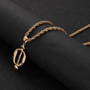 Détail du pendentif couronne lettre O dorée avec croix étoilée sur support noir