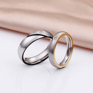 Polished silver and gold-tone titanium couple rings with zircon on elegant silk background